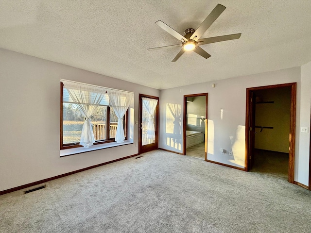 unfurnished bedroom with carpet, ceiling fan, a walk in closet, and a textured ceiling