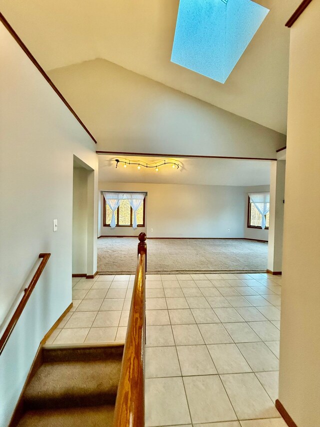 interior space with vaulted ceiling with skylight and light tile patterned flooring