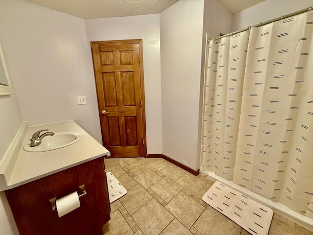 bathroom with curtained shower, vanity, and a textured ceiling