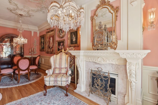 living area featuring a high end fireplace, hardwood / wood-style flooring, a chandelier, and ornamental molding