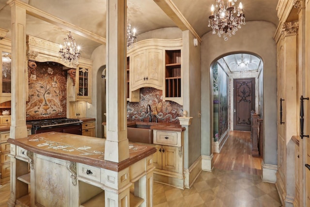 kitchen with butcher block counters, sink, tasteful backsplash, vaulted ceiling, and cream cabinetry