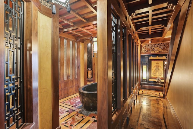 corridor featuring coffered ceiling and wood walls