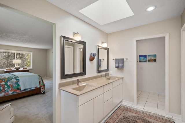 ensuite bathroom with double vanity, a sink, connected bathroom, and a skylight