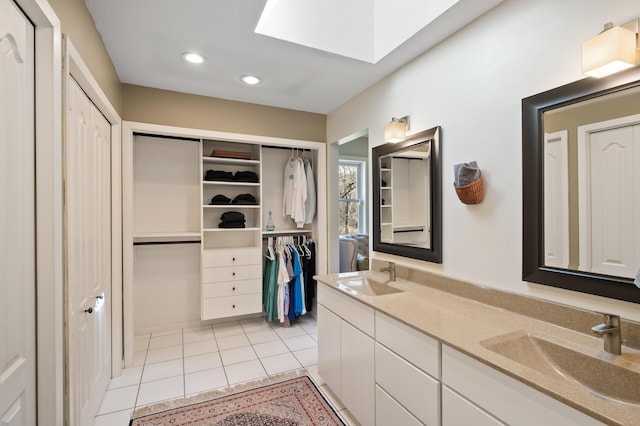 bathroom with double vanity, a skylight, a sink, and tile patterned floors