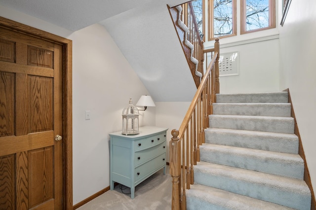 stairs with vaulted ceiling, baseboards, and carpet flooring