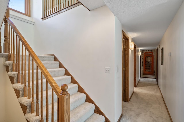 staircase featuring baseboards and carpet