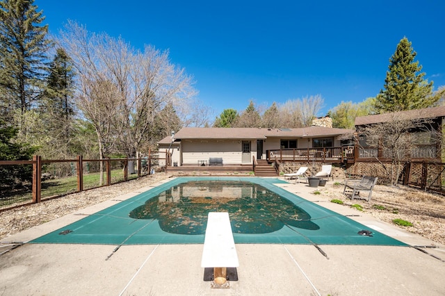 view of swimming pool featuring a fenced in pool, a diving board, fence, and a deck