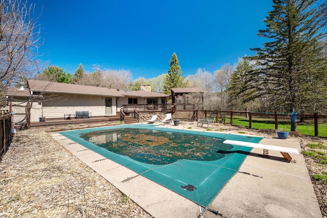 view of swimming pool featuring a diving board, a wooden deck, a fenced in pool, a fenced backyard, and a patio