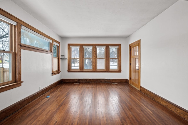 unfurnished room featuring dark wood-style floors and baseboards