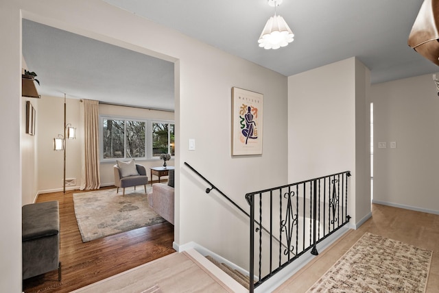 corridor featuring wood finished floors, an upstairs landing, and baseboards