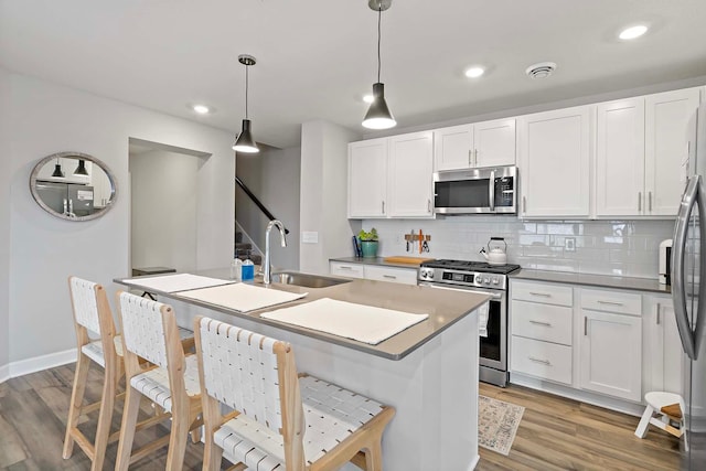 kitchen featuring sink, stainless steel appliances, white cabinetry, and pendant lighting