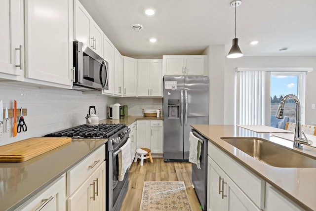 kitchen with sink, white cabinetry, hanging light fixtures, and stainless steel appliances