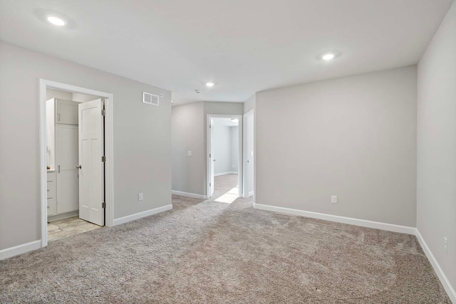 unfurnished bedroom featuring light colored carpet and a walk in closet