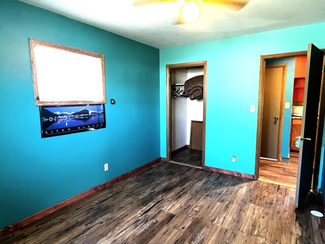 unfurnished bedroom with dark hardwood / wood-style flooring, ceiling fan, and a closet