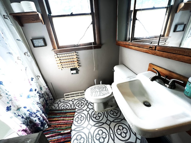 bathroom featuring toilet, plenty of natural light, tile patterned flooring, and sink