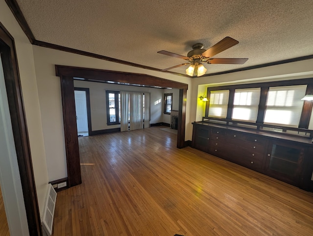 empty room featuring hardwood / wood-style floors, ornamental molding, a textured ceiling, and ceiling fan