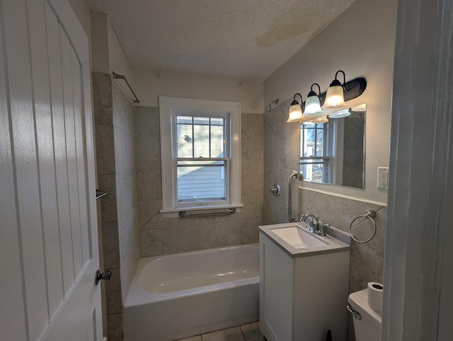 full bathroom with tile walls, tiled shower / bath combo, vanity, toilet, and a textured ceiling