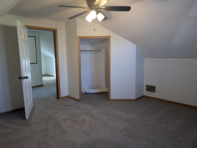 unfurnished bedroom featuring ceiling fan, carpet flooring, vaulted ceiling, and a textured ceiling