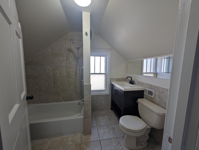 full bathroom with tile walls, vanity, vaulted ceiling, toilet, and tiled shower / bath