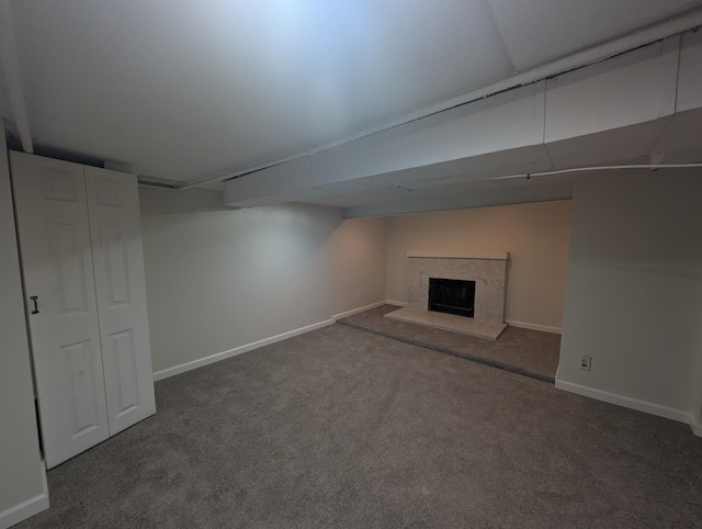 basement featuring dark carpet and a high end fireplace