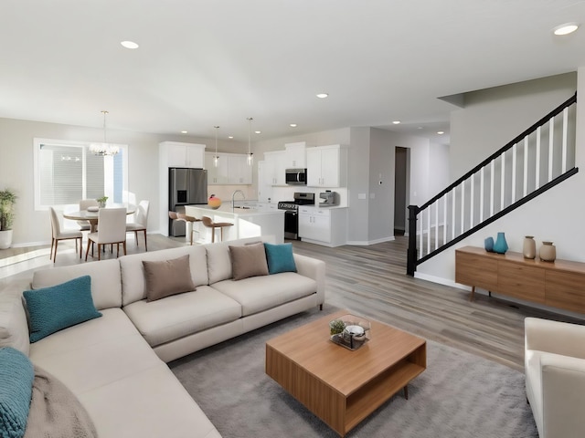 living room featuring an inviting chandelier, sink, and hardwood / wood-style floors