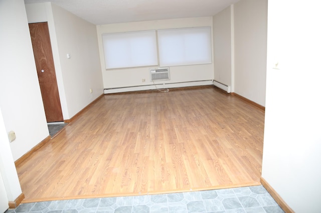 spare room featuring an AC wall unit, wood-type flooring, and baseboard heating