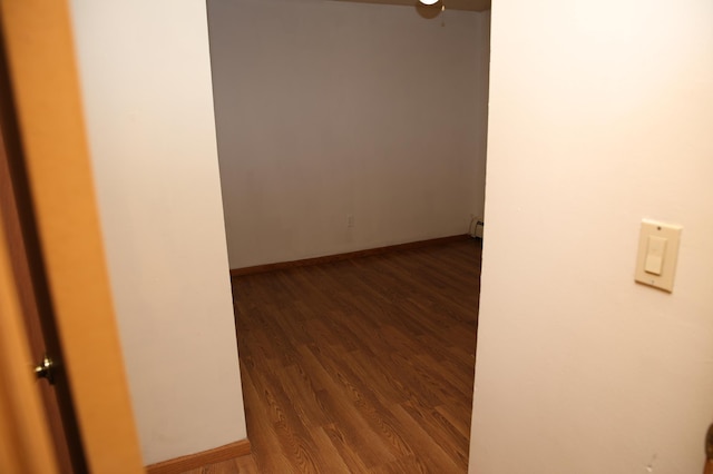 spare room featuring baseboard heating and dark wood-type flooring