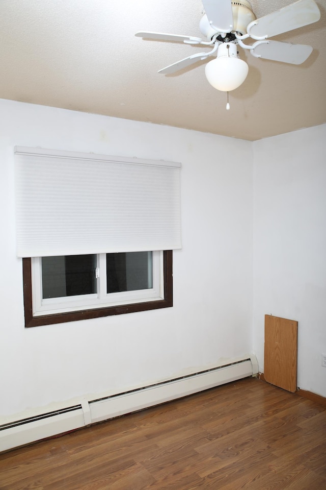 empty room with dark hardwood / wood-style floors, baseboard heating, and ceiling fan