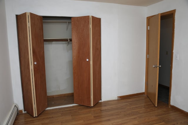 unfurnished bedroom featuring baseboard heating and dark wood-type flooring