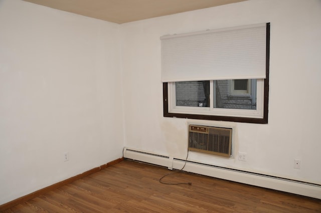 unfurnished room with a baseboard radiator, a wall mounted air conditioner, and wood-type flooring