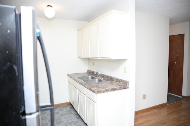 kitchen featuring white cabinetry, fridge, and sink