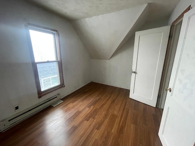 additional living space featuring dark hardwood / wood-style flooring, a baseboard radiator, and vaulted ceiling