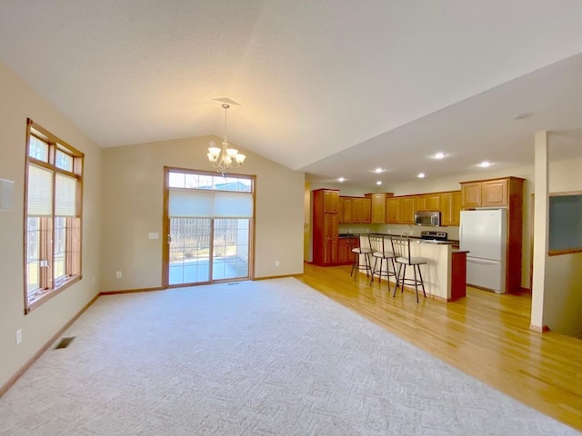 living room featuring vaulted ceiling, an inviting chandelier, and light hardwood / wood-style flooring