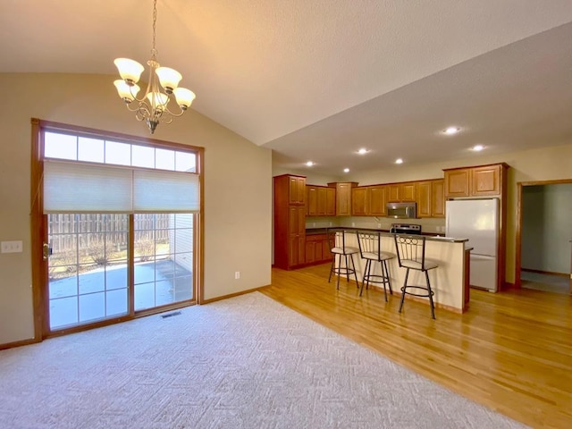 kitchen with decorative light fixtures, a kitchen island, a kitchen bar, an inviting chandelier, and stainless steel appliances