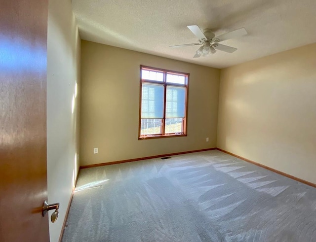 carpeted spare room with ceiling fan and a textured ceiling