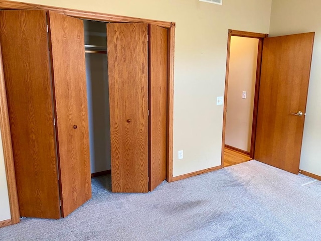 unfurnished bedroom with light colored carpet and a closet