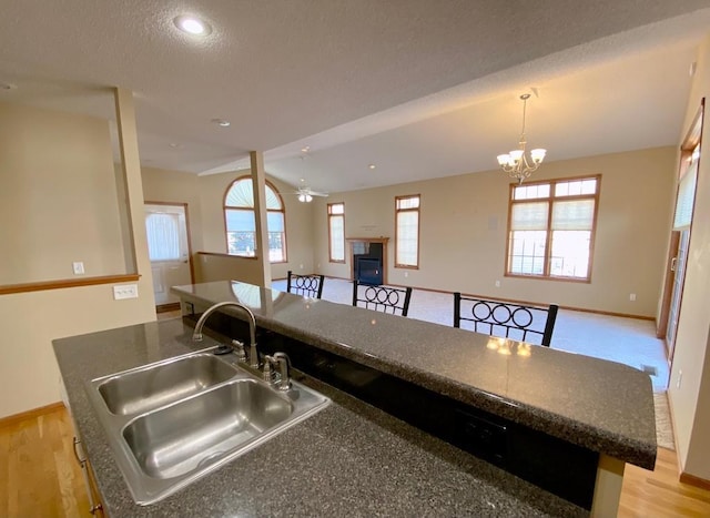 kitchen with pendant lighting, sink, light hardwood / wood-style flooring, an island with sink, and ceiling fan with notable chandelier