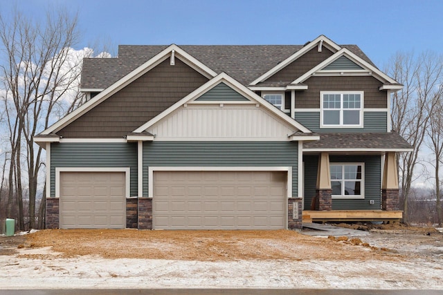 craftsman-style home with stone siding, a shingled roof, an attached garage, and driveway