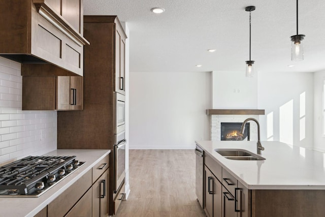 kitchen with appliances with stainless steel finishes, backsplash, hanging light fixtures, and sink