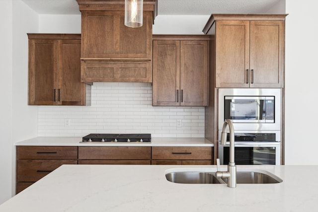 kitchen featuring tasteful backsplash, light stone counters, sink, and appliances with stainless steel finishes