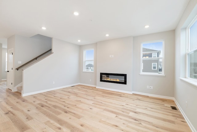 unfurnished living room featuring light wood-type flooring and a healthy amount of sunlight