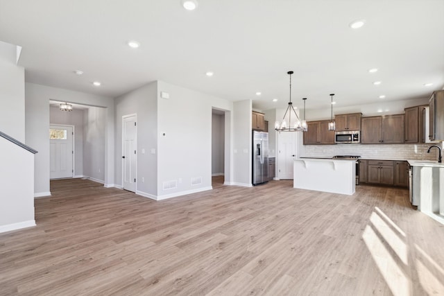 kitchen featuring hanging light fixtures, sink, appliances with stainless steel finishes, tasteful backsplash, and a kitchen island