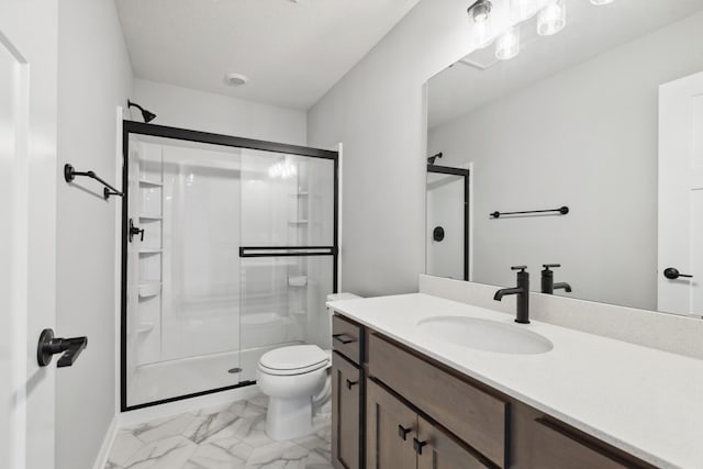 bathroom featuring vanity, a shower with shower door, and toilet