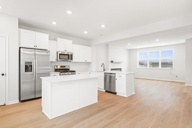 kitchen featuring a center island, white cabinets, decorative backsplash, light wood-type flooring, and stainless steel appliances