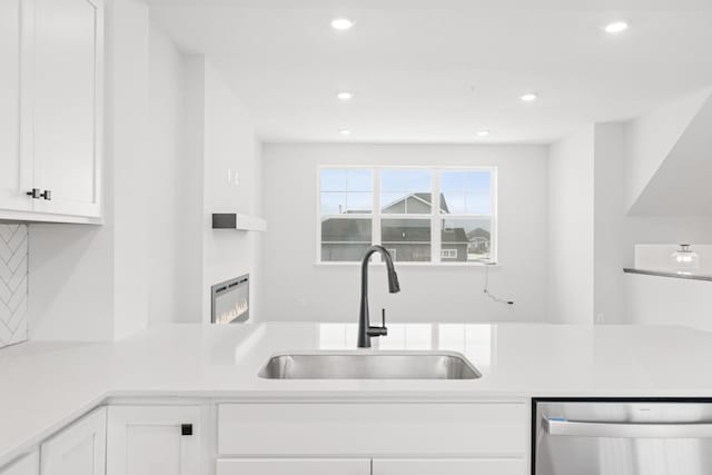 kitchen featuring white cabinets, decorative backsplash, stainless steel dishwasher, and sink