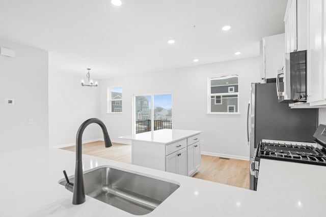 kitchen with sink, pendant lighting, an inviting chandelier, a center island, and white cabinetry