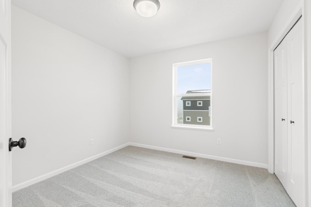 unfurnished bedroom featuring light carpet and a closet