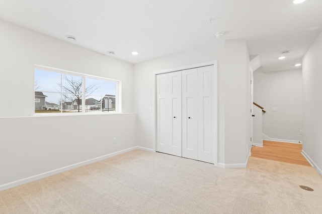 unfurnished bedroom with light colored carpet and a closet