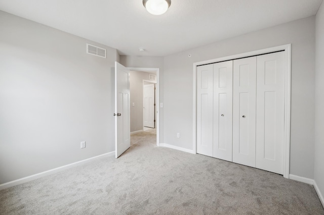 unfurnished bedroom with light carpet and a closet