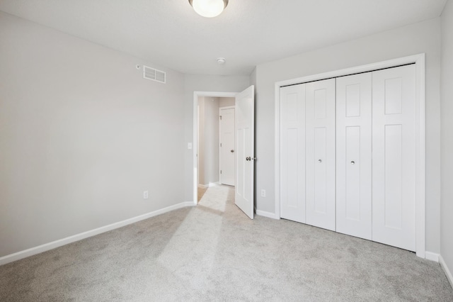 unfurnished bedroom with light colored carpet and a closet